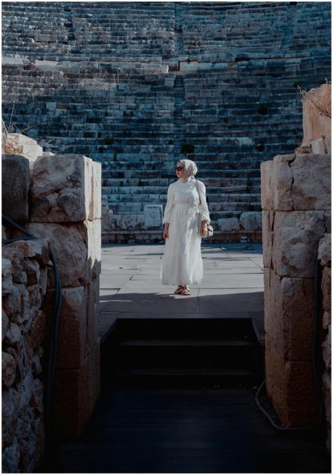 Woman in white dress and hijab stands in historic