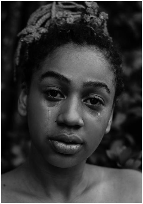 A black and white portrait of a young woman expres