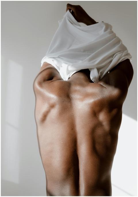 Rear view of a muscular man lifting shirt, showcas