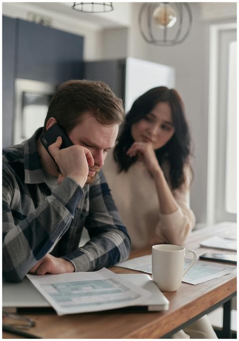 A worried couple sits at a table with bills and a