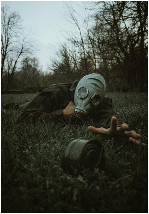 A person wearing a gas mask reaches across the gra