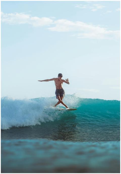 Surfer rides a powerful wave under the blue sky in