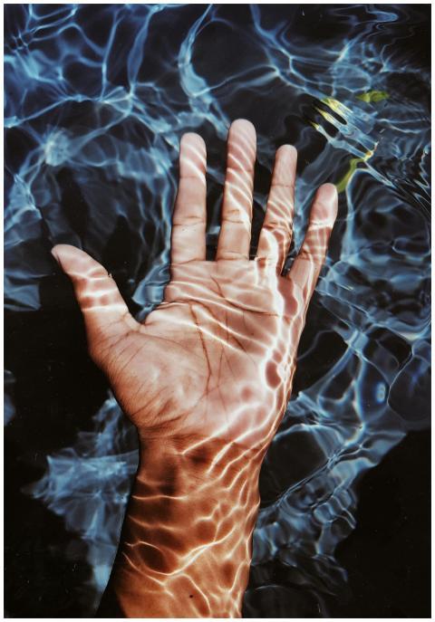 A hand submerged in clear blue water with captivat