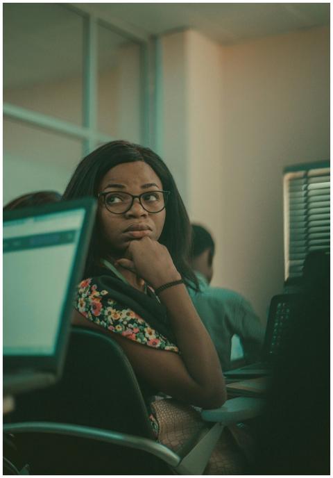 A young woman in a classroom setting using laptops