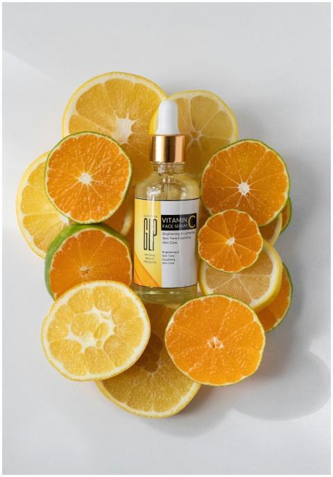 Vitamin C serum bottle surrounded by fresh orange