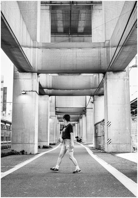 Black and white photo of a pedestrian under an urb
