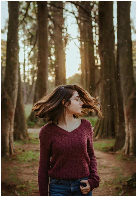 A young woman twirls in a forest, capturing the es