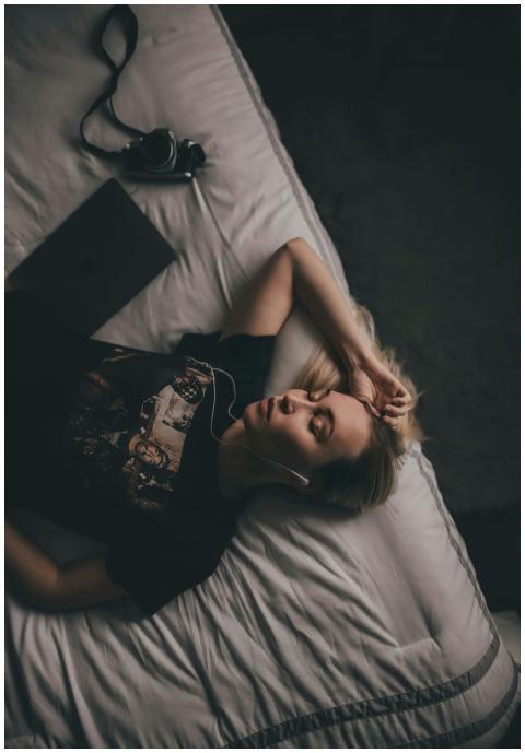 A woman lying on a bed listening to music with ear