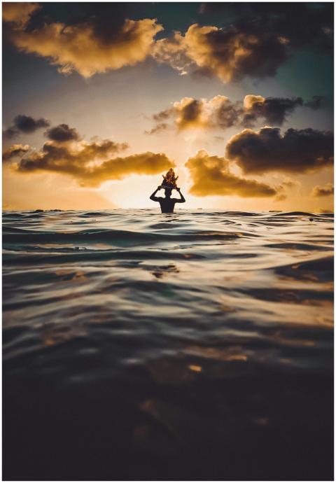 A silhouette of a person enjoying the ocean at sun