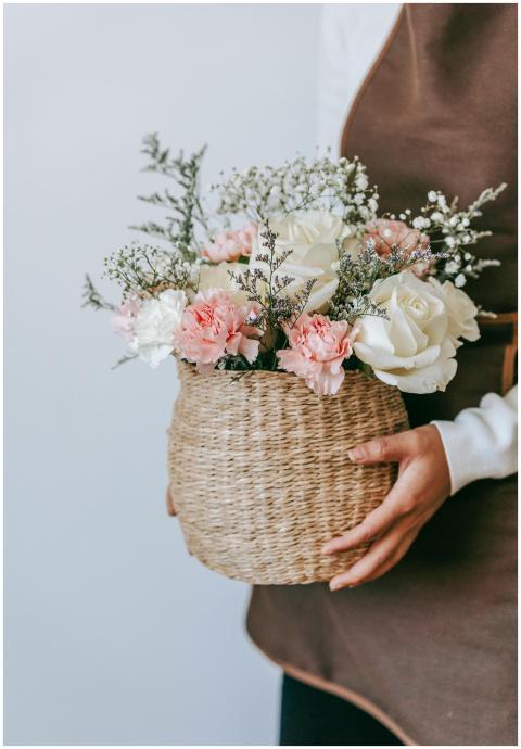 Crop anonymous female in apron standing with wicke