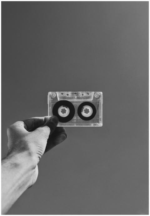 Hand holding a classic cassette against a plain ba