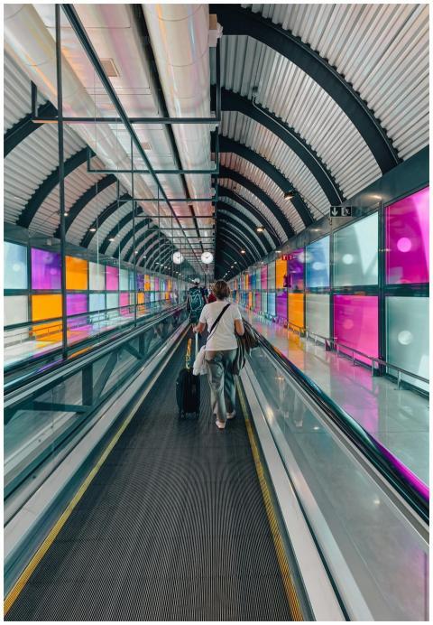 A traveler with a suitcase on a vibrant moving wal