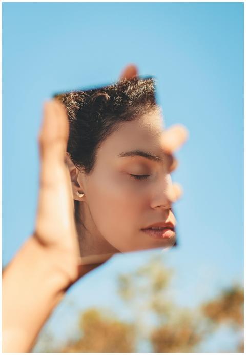 A serene woman holds a mirror with her reflection