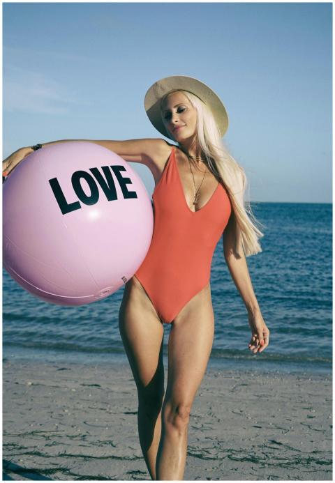 Young woman in swimsuit holding a pink love ball o