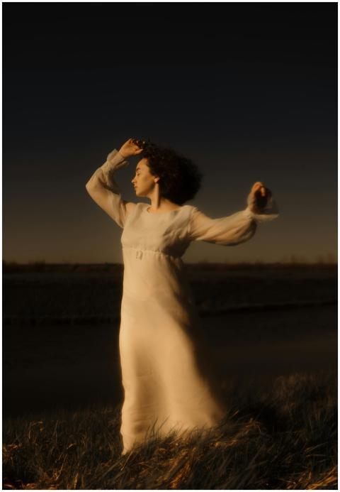 A serene woman in a flowing white dress poses in a