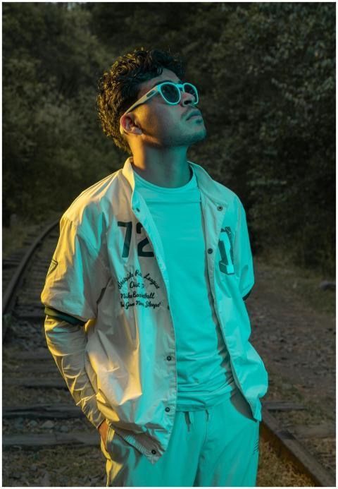 Man in trendy attire and sunglasses poses on an ab