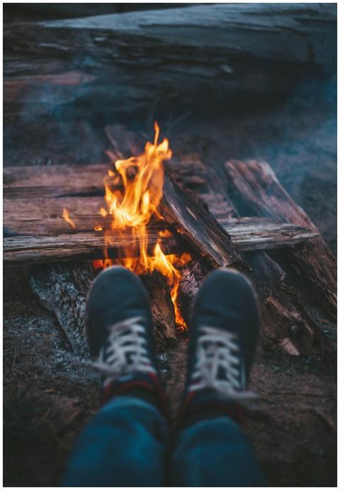 Close-up of feet warming by a campfire in a rustic