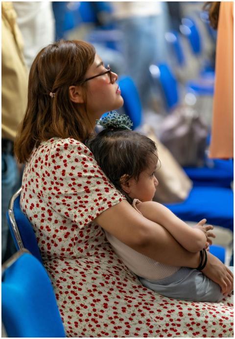A mother and daughter sit in a busy setting, offer