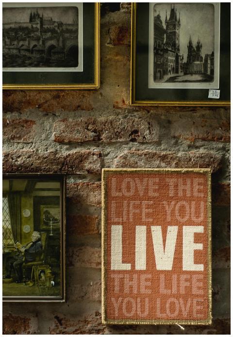 Art and frames adorn a rustic brick wall, featurin