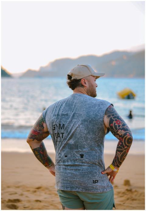 Tattooed man on a sandy beach looking at the sea d
