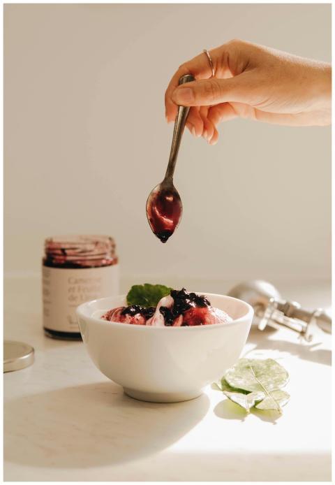 Close-up of a hand adding jam to berry ice cream i