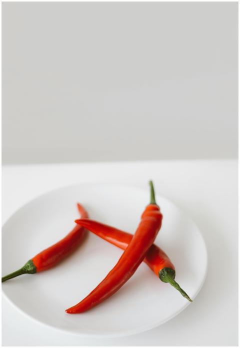 Vibrant red chili peppers on a white plate, showca