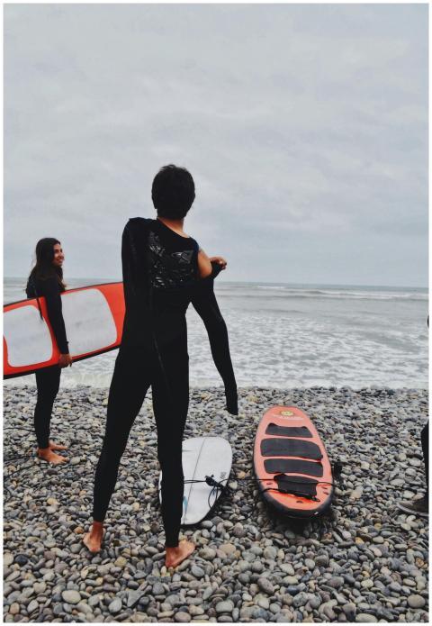 Group of surfers in wetsuits preparing by the ocea