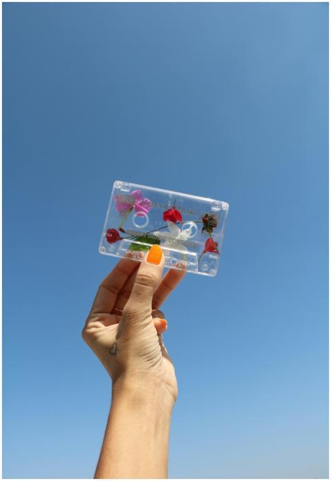 A hand with painted nails holds a flower-decorated
