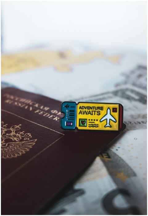 A Russian passport with an 'Adventure Awaits' pin