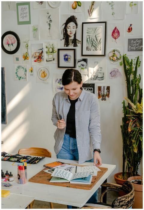 Cheerful young female designer in jeans standing n