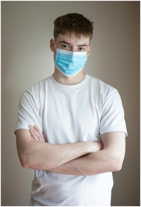 Portrait of young man wearing a mask, arms crossed