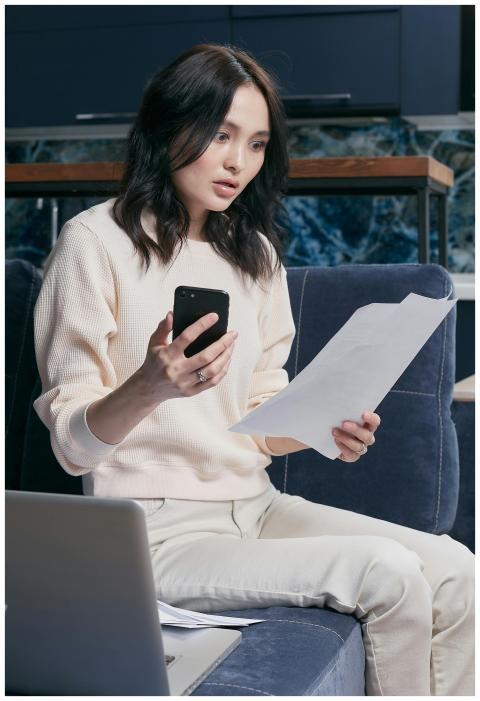 A young woman uses her smartphone and laptop to ma