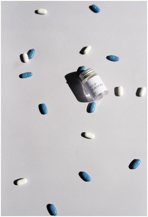 Jar of pills and scattered blue and white tablets