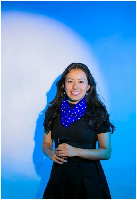 Smiling woman holding a microphone, wearing black