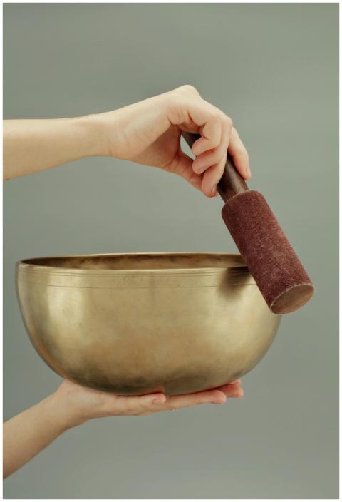 A close-up of hands holding a Tibetan singing bowl
