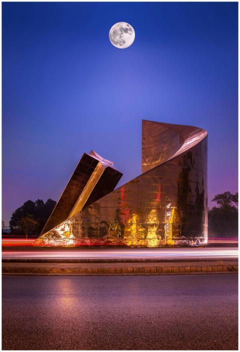Modern sculpture illuminated under a full moon in