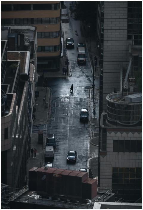 A dark, rainy street view of London with cars and