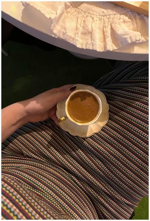 Elegant coffee cup held over colorful attire, perf