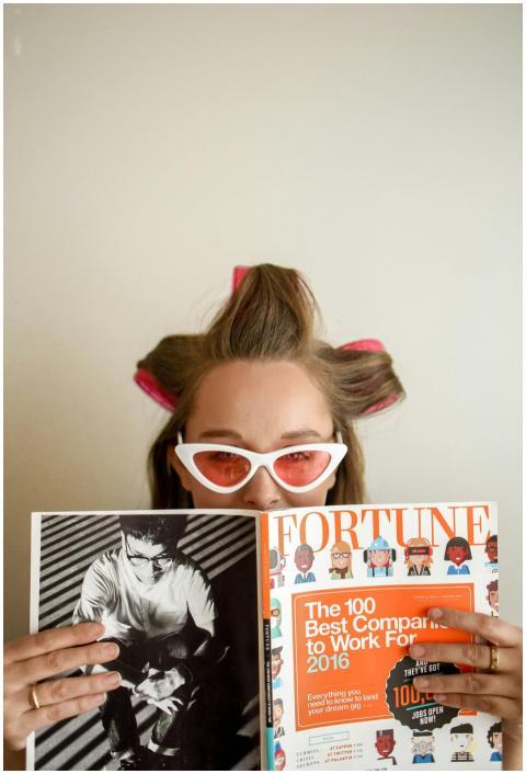 A woman with hair rollers reads a Fortune magazine