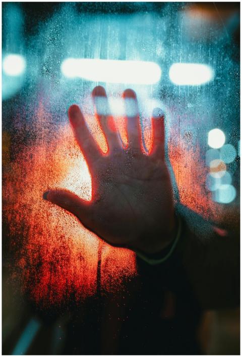 A dramatic depiction of a hand pressed against a f