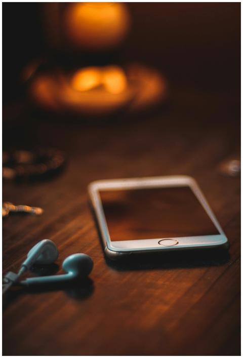 Mobile phone with earphones on a wooden table in w