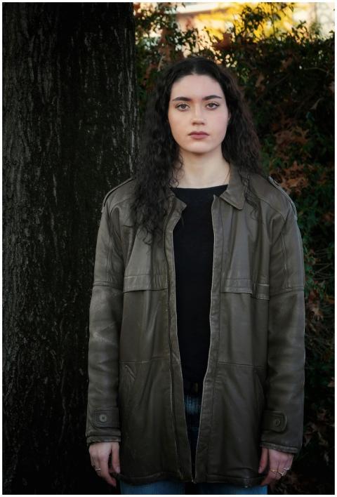 Young woman standing in front of a tree wearing a