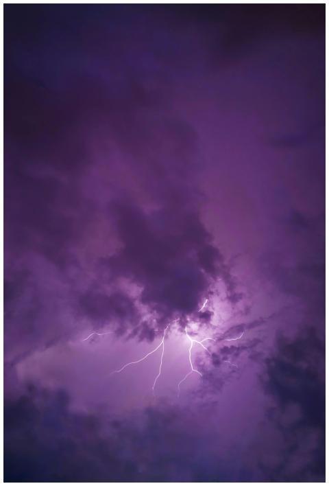 A vivid lightning strike illuminates dark clouds d