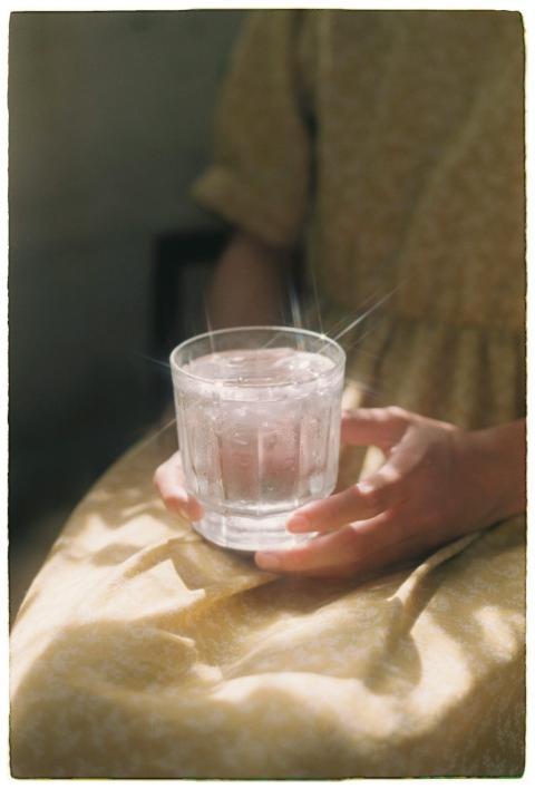Hands holding a glass of water sparkling in soft s