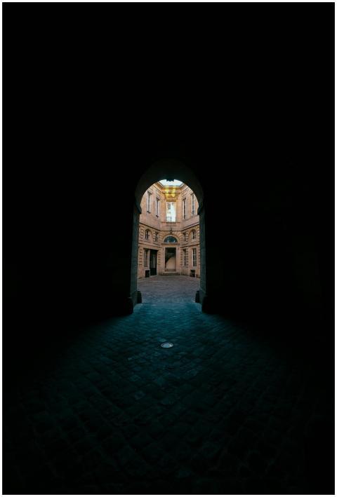 Explore a historic courtyard through a gothic arch