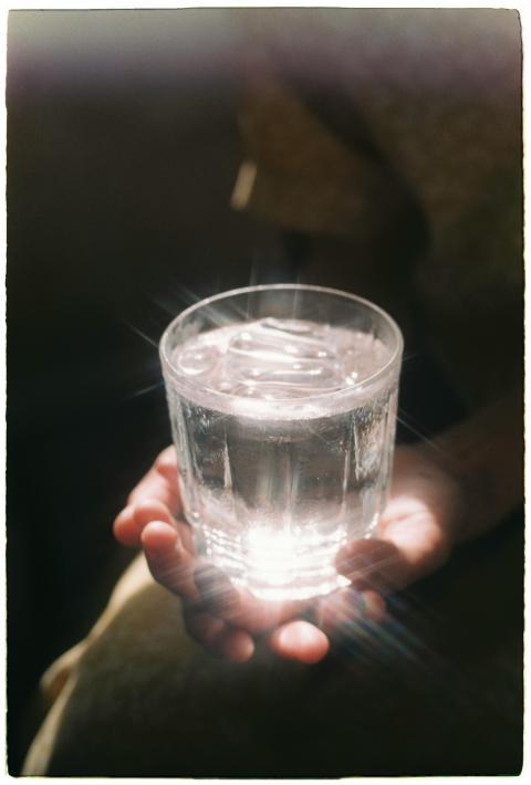 Crystal clear glass of water held gently, highligh