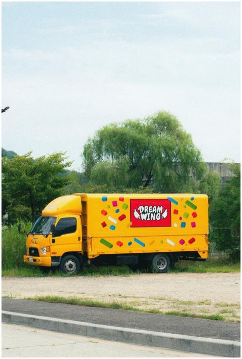 A bright yellow Dream Wings truck parked on a sunn