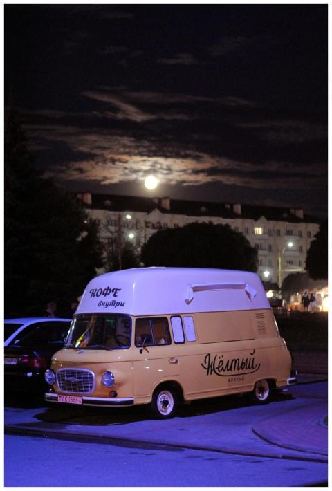 A charming vintage yellow van parked under a full