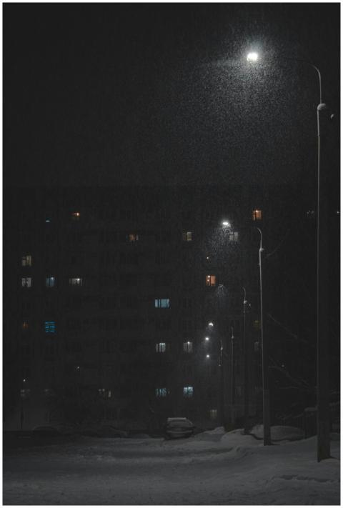 Snow gently falling on a quiet street at night, li