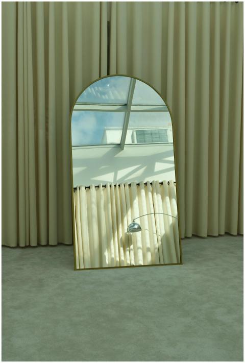 A stylish mirror reflects a sunlit interior with c